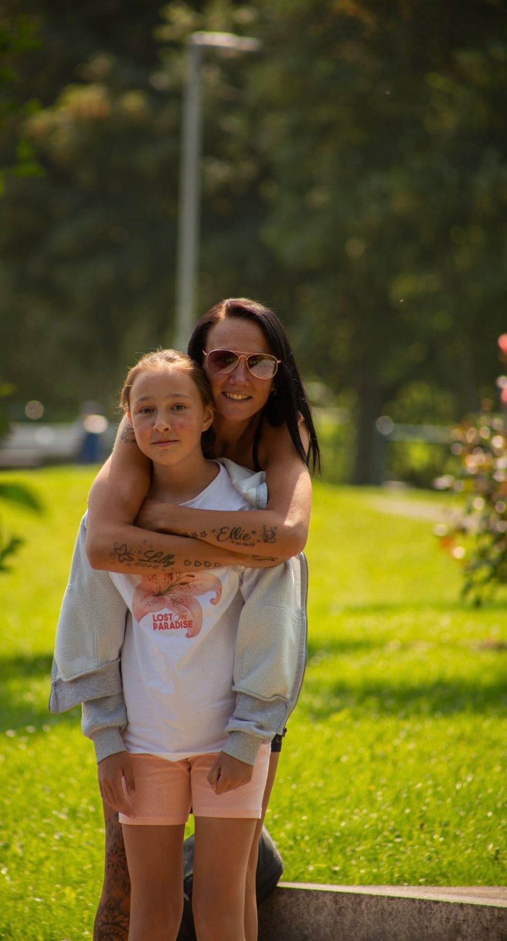 Mum hugging her daughter in a sunlit park